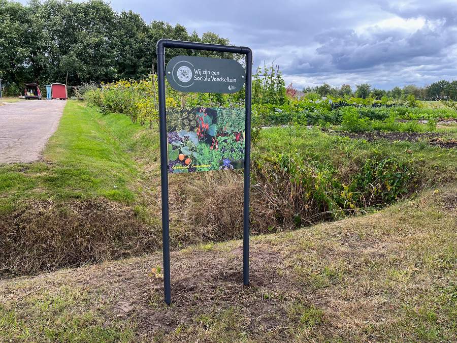 Het bord aan de straatkant zegt dat we een officiële sociale voedseltuin zijn.